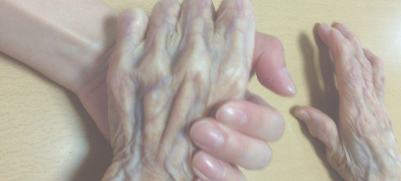 支える側の手が、高齢の方の手をやさしく包み込んでいる様子
